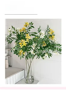 Detail of yellow and white faux jasmine flowers in a clear glass vase for home decor