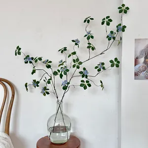 Enredadera de loto artificial estilo Zen con flores azules en un jarrón de vidrio
