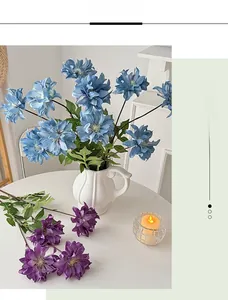 Detail of blue and purple artificial dahlia flowers in a white wavy ceramic vase