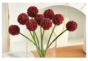 Close-up of nine burgundy artificial globeflower stems in a clear glass vase for decor