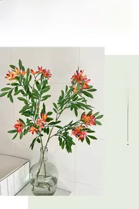 Detailed close-up of artificial flowers with orange gradient petals in a glass vase