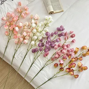 Faux lantern fruit flower branches in various colors arranged on white bedding decor