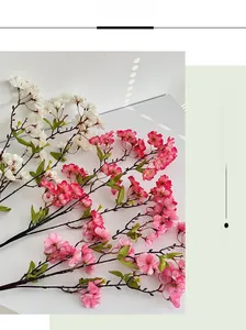 Close-up of realistic artificial cherry blossom branches with dense petals and small green leaves