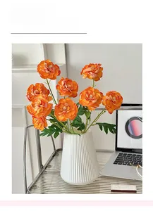 Detail of orange artificial peonies in a white ribbed ceramic vase for home decor