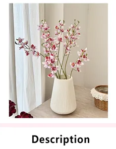 Pink and purple artificial orchids in a white ribbed ceramic vase on a wooden table
