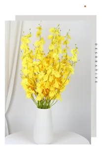 Close-up of bright yellow Oncidium orchid petals in a textured white ceramic vase