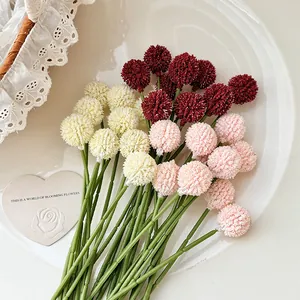 Artificial craspedia pompom bouquet in red, white and pink colors on white ceramic tray