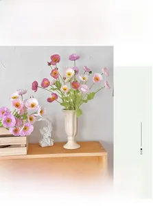 Detail of colorful artificial poppy flowers in a cream ceramic vase with angel decor