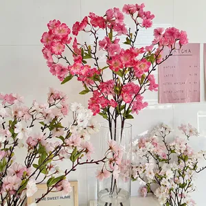 Artificial cherry blossom silk flower stems in vase for home wedding decoration