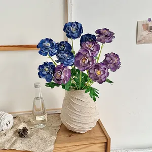 Artificial Ranunculus flowers in navy and purple within a textured ceramic vase