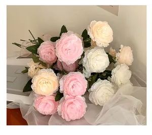 Detail of pink and white silk ranunculus flowers with soft petals and green leaves