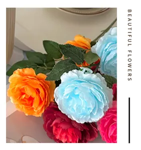 Detailed close-up of artificial peony silk flowers in orange, blue and pink with green leaves