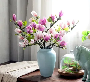 Détail de fleurs de magnolia artificielles aux pétales dégradés dans un vase bleu