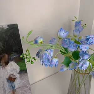 Faux blue Delphinium in a glass vase against an artistic oil painting background