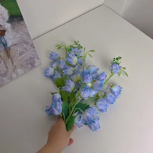 Detail of blue purple gradient artificial silk flowers held against a white wall