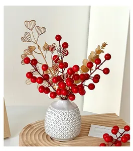 Detail of red faux berries and golden wire heart leaves in a white textured vase