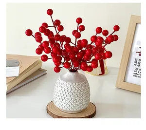 Close-up of artificial red berries in a textured white ceramic vase for home decoration