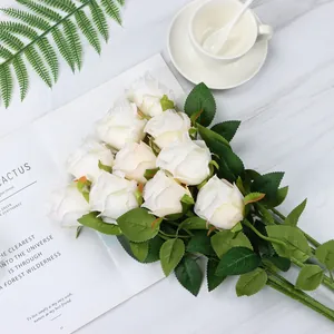 Detail shot of artificial white Bulgarian roses with realistic petals on marble surface