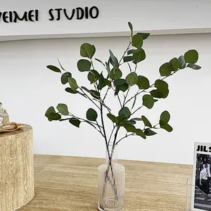 Artificial eucalyptus leaves in a ribbed glass vase on a wooden desk for home decor