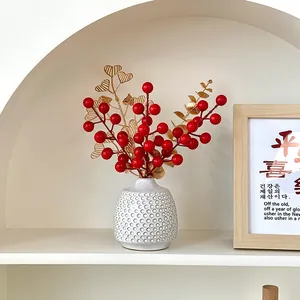 Artificial red berry and golden leaf arrangement in a white honeycomb ceramic vase