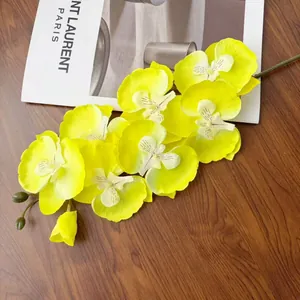 Dettaglio di ramo di orchidea artificiale gialla con fiori in seta su sfondo di legno