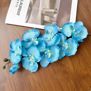 Dettaglio di orchidea farfalla blu artificiale con petali sfumati su fondo legno
