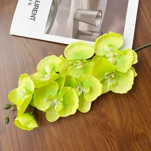 Dettaglio dell'orchidea artificiale verde lime con petali e boccioli su legno scuro