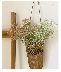 Pink and white faux gypsophila flowers in a rustic woven hanging basket on a white wall