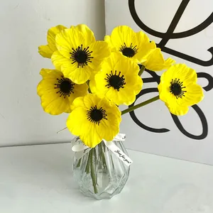 Fiori di papavero finti gialli in un vaso di vetro sfaccettato per decorazione casa