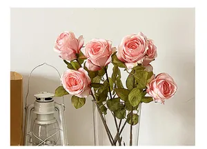 Detalle de rosas artificiales con bordes quemados en jarrón de vidrio para decoración