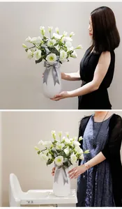 Detailed view of artificial white Eustoma flowers in a vase with grey ribbon bow decoration