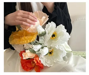 Primo piano di papaveri artificiali colorati con petali realistici tenuti in mano
