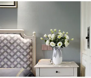 Artificial white Lisianthus flowers in a ceramic vase with a grey bow for home decor