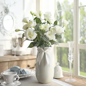 Artificial white lisianthus flowers in a ribbed ceramic vase with a silk bow for home decor