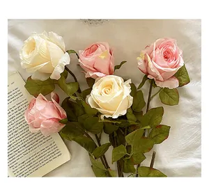 Detalle de rosas artificiales vintage con bordes quemados en rosa y crema con hojas