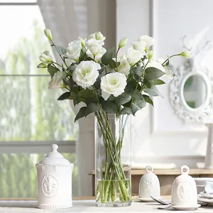 Detailed view of white artificial Eustoma flowers in a clear cylindrical glass vase