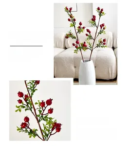 Detail of lifelike artificial pomegranate branch with red berries in white ceramic vase