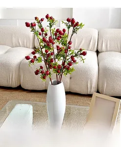 Detailed close-up of artificial pomegranate branches in a white ceramic vase decoration