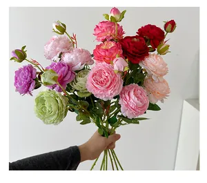 Close-up of artificial peony and rose bouquet with realistic silk petals and green leaves
