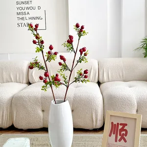 Artificial red pomegranate stems in white ceramic vase for home decor accents