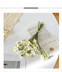 Close-up of white chamomile faux flowers on lace tablecloth with vintage book pages