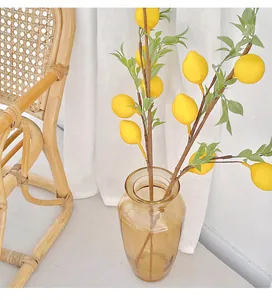Detailed view of artificial lemon branch in brown glass vase for home decoration