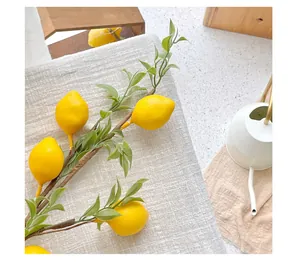 Detail of artificial lemon branch with realistic yellow fruit and green leaves on fabric