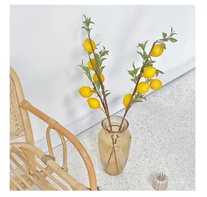 Detail of artificial lemon branches with yellow fruits in a glass vase for home decor