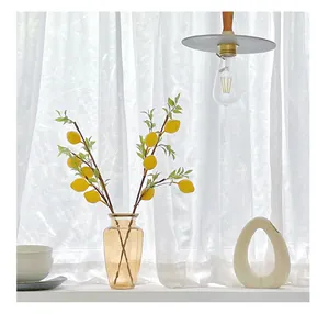 Detailed view of artificial lemon branch with yellow fruits in an amber glass vase