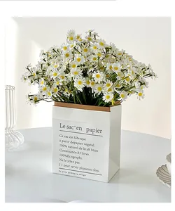 Close-up of artificial white chamomile daisies in a minimalist kraft paper bag vase