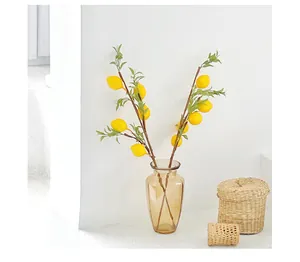Artificial lemon branches in amber glass vase with woven baskets for home decor
