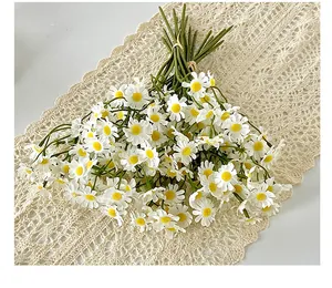 Close-up of white chamomile faux flowers on a delicate white lace table runner