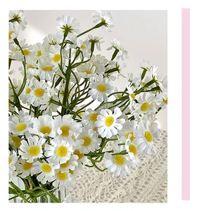 Close-up of faux chamomile daisies in a ribbed glass vase on a lace tablecloth