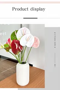 Colorful 3D printed Anthurium flowers in a white ceramic vase on a wooden table